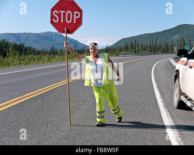 Datenverkehr zu steuern, Frauen tragen Sicherheit Farben, mit'stop' Zeichen, Alcan Highway. Stockfoto