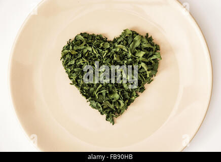 Herzform getrocknete Petersilie auf den Teller. Zum Valentinstag. Symbol der Liebenden. Stockfoto