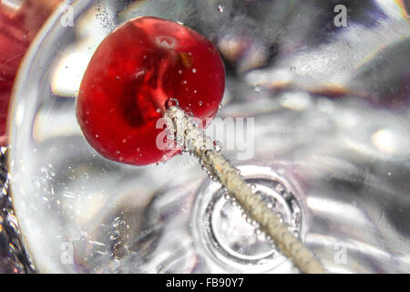 Kirsche auf einen Cocktailspieß in ein Glas Wein, Mineralwasser auf Alufolie Hintergrund. Stockfoto