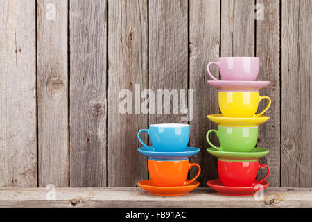 Farbenfrohe Kaffeetassen auf Regal gegen rustikale Holzwand mit Textfreiraum Stockfoto