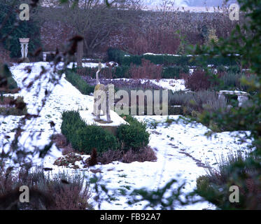 Statue eines steinernen Löwen in einem großen schneebedeckten Land-Garten im winter Stockfoto