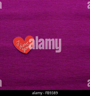 Liebesbotschaft mit roten Herz auf lila Tuch Stockfoto