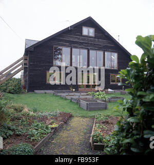 Hochbeeten mit hölzernen Einfassung im Garten des dunklen Holz Schindeln Haus auf dem Land Stockfoto