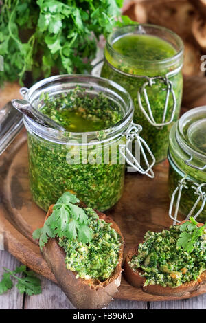 Hausgemachte Koriander Pesto in Gläsern auf hölzernen Hintergrund Stockfoto