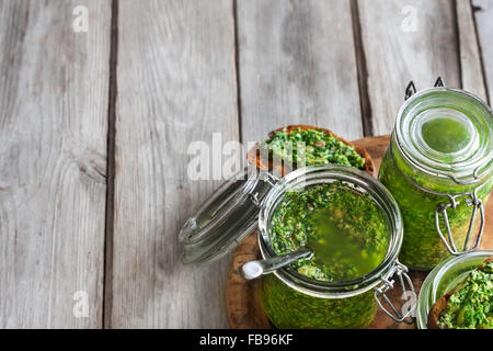 Hausgemachte Koriander Pesto in Gläsern auf hölzernen Hintergrund Stockfoto