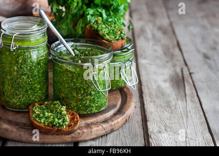 Hausgemachte Koriander Pesto in Gläsern auf hölzernen Hintergrund Stockfoto