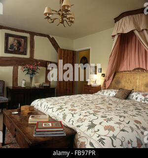 Coronet mit rosa Vorhängen über Bett mit floralen Bettdecke in neunziger Jahre Ferienhaus Schlafzimmer Stockfoto