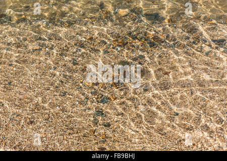 Transparent, klares Wasser und Kies mit Sonnenlicht Reflexion Stockfoto