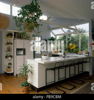 Schwarze Metall Stühle an Frühstücksbar in Erweiterung der Küche mit einem großen Kühlschrank und grünen Pflanzen Stockfoto