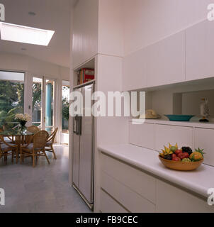 Großer Kühlschrank mit Gefrierfach in weißen Architektur Küche mit Rohrstock zurück Stühle an einem Tisch aus Glas Stockfoto