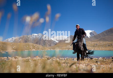 Tsaganaa, ein Führer und Herder, Reiten in der Nähe von einem Gletschersee in der abgelegenen Kharkhiraa Turgen Nationalpark, Mongolei. Stockfoto