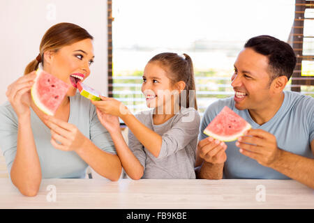 entzückende kleine Mädchen ihrer Mutter ein Stück Wassermelone verleihen Stockfoto