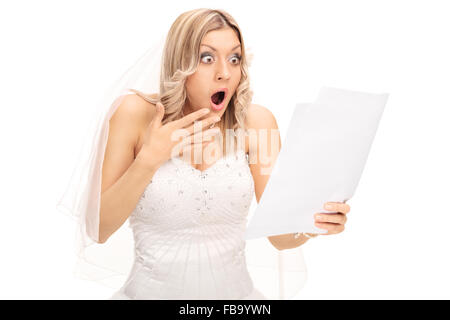 Schockiert blonde Braut Blick auf ein Stück Papier in Unglauben isoliert auf weißem Hintergrund Stockfoto