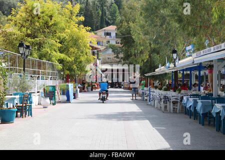 Ein einsamer Moped Fahrer auf ein Grieche, Taverne gesäumten Straße in Vasiliki, Griechenland. Stockfoto