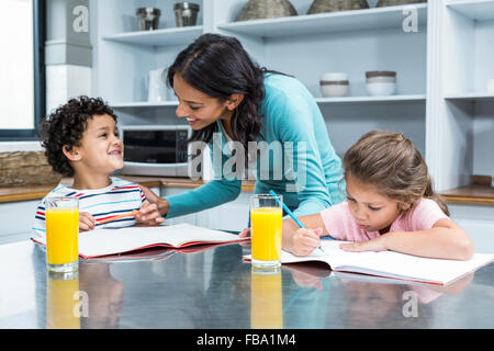 Gute Mutter ihren Kindern Hausaufgaben zu helfen Stockfoto