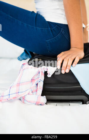 Frau sitzt auf ihrem übervoll-Koffer Stockfoto