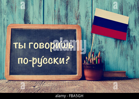 eine Tafel mit der Frage sprichst du Russisch? in Russisch, einen Topf mit der Flagge von Russland, Bleistifte und einige Bücher geschrieben, Stockfoto