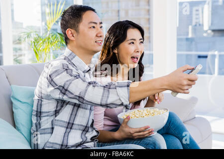 Fröhlicher junger Paare sitzen auf einem Sofa Stockfoto