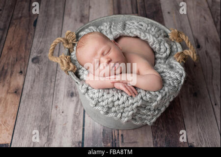 Neugeborenes Babyjungen schlafen in einem Eimer Stockfoto