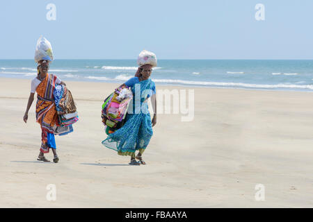 Zwei indische Frauen verkaufen Sarongs und Stoffe Spaziergang entlang eines leeren Strand, Mandrem Beach, North Goa, Indien Stockfoto