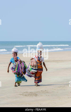 Zwei indische Frauen verkaufen Sarongs und Stoffe Spaziergang entlang eines leeren Strand, Mandrem Beach, North Goa, Indien Stockfoto