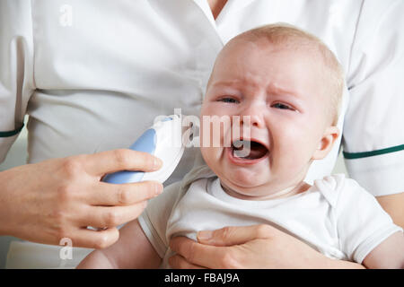 Krankenschwester, Einnahme von Weinen des Babys Temperatur mit Digitalthermometer Stockfoto