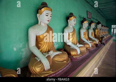 Lange Reihe von bemalten Stein Wand Buddhas gegen ein grüner Tempel in der alten Hauptstadt von Sagaing Myanmar Stockfoto