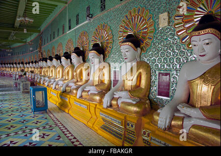 Lange Reihe von bemalten Stein Wand Buddhas gegen ein grüner Tempel in der alten Hauptstadt von Sagaing Myanmar Stockfoto