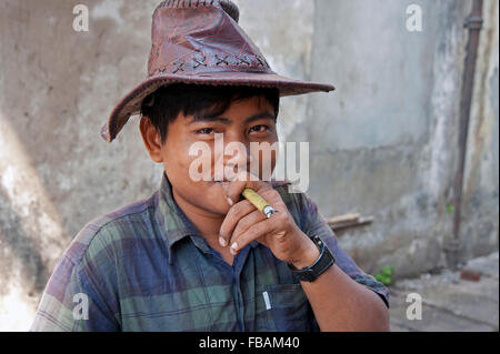 Porträt eines glücklich lächelnde birmanischen mit braunem Leder Hut Rauchen eine burmesische Cheroot eine einfache Steinmauer Yangon Myanmar Stockfoto