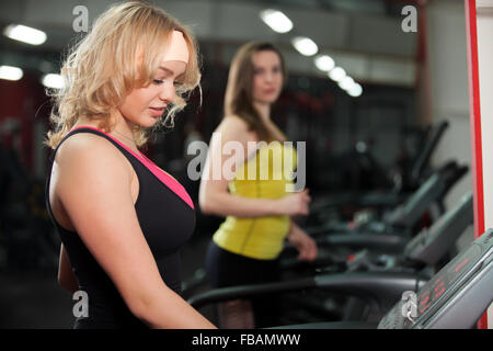 Sportliches Girl is gonna auf Cardio Trainer, Rennstrecke im Fitness-Studio trainieren Stockfoto