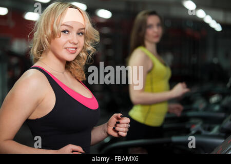 Lächelnd sportliches Girl auf Cardio Trainer, läuft auf der Rennstrecke im Fitness-Studio trainieren Stockfoto