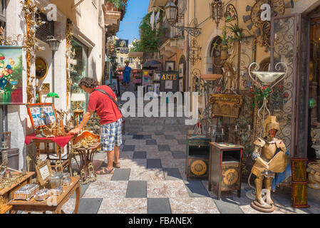 Shopping in Sizilien Taormina, Ansicht eines Touristen, der Waren vor einem Antiquitätengeschäft im Corso Umberto l in der Altstadt von Taormina, Sizilien, untersucht. Stockfoto