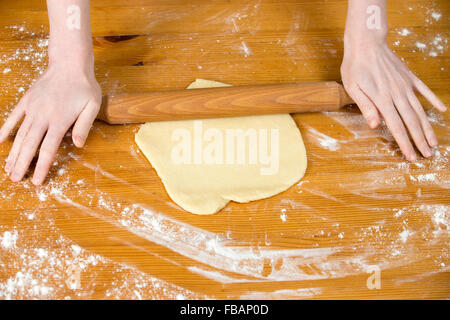 Hausgemachte Küche, weiblichen Händen ausrollen Teig mit Nudelholz auf Holztisch mit Mehl bedeckt Stockfoto