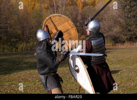 Zwei Krieger im alten russischen Rüstungen rekonstruierten mittelalterlichen Kampf mit Schwertern auf dem Schlachtfeld. Stockfoto