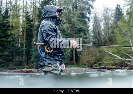 Männliche Angler Fliegenfischen in einem Fluss im Regen auf der Olympic Peninsula in Washington State. Stockfoto