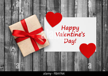 Valentinstag Karte mit Geschenk-Box und roten Herzen auf schwarz / weiß aus Holz Hintergrund Stockfoto