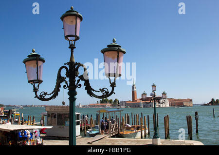 Venezianische Straßenlaternen mit dem Canale Grande und die Kirche von San Giorgio Maggiore in der Ferne, Venedig, Italien. Stockfoto