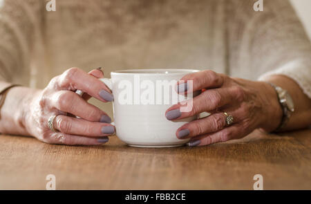 Ältere Womans Hände halten eine Tasse Stockfoto