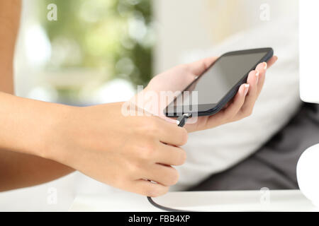 Frau Hände einstecken eine Ladegerät in ein smart Phone im Schlafzimmer zu Hause Stockfoto