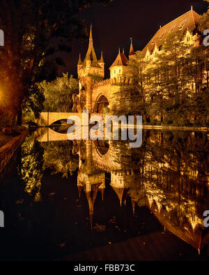 Blick auf das Eingangstor, Turm und Brücke des Schlosses Vajadahunyad spiegelt sich in einem See in der Nacht, Budapest, Ungarn Stockfoto