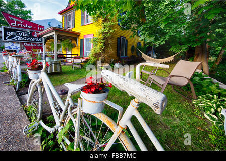 Street Art von Fahrrädern zum Zaun in ein lebendiges Gelb gemalte Haus mit alten Schildern, Lambertville, New Jersey Stockfoto