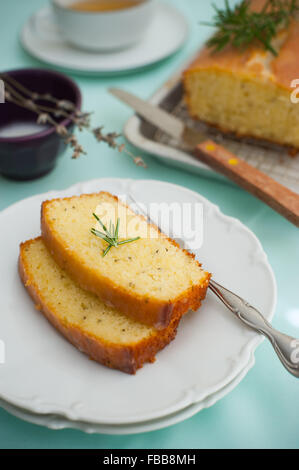 Kuchen zum Tee: Scheiben auf gestapelten weißen Tellern mit Rosmarin Blätter garnieren und Kuchen Brot im Hintergrund Stockfoto