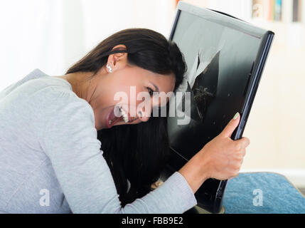 Brunette hispanische Modell hält gebrochene schwarzer Bildschirm beim smashing Kopf hinein. Stockfoto