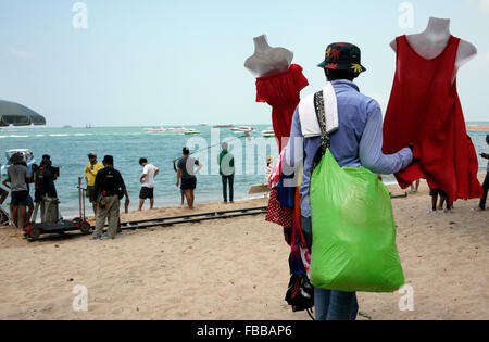 Ein Strand-Anbieter schaut zu, wie eine Szene aus einem Thai Seifenoper am Strand von Pattaya Thailand gefilmt wird Stockfoto