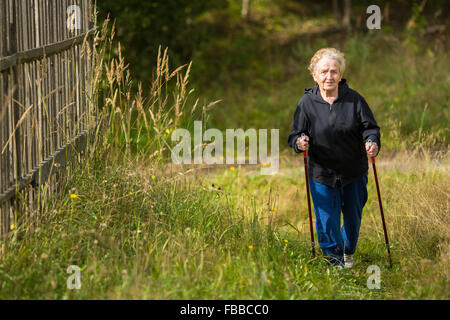 Eine ältere Frau Praktiken Nordic-walking im Park. Stockfoto