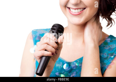 Lächelnde junge Frau im glitzernden blauen Kleid, singen, Mikrofon, close-up der mic, isoliert auf weißem Hintergrund, Kopie s halten Stockfoto