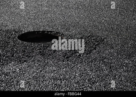 Städtische Straße im Bau, Asphaltierung im Gange. Offener Abwasserkanal Schacht unter frischen schwarzen Asphaltschicht Stockfoto