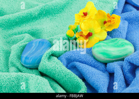 Bunte Seifen, Handtücher und Blumen-Nahaufnahme-Bild. Stockfoto