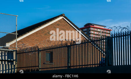 Ein Belfast Peacewall teilt die Wasserfälle und Shankill Straßen mit Divis Hochhaus mit Blick auf die Umgebung. Stockfoto