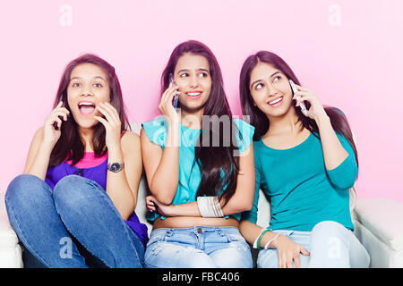 3 indische Junge Womans Freunde sitzen Sofa Talkng Handy Stockfoto